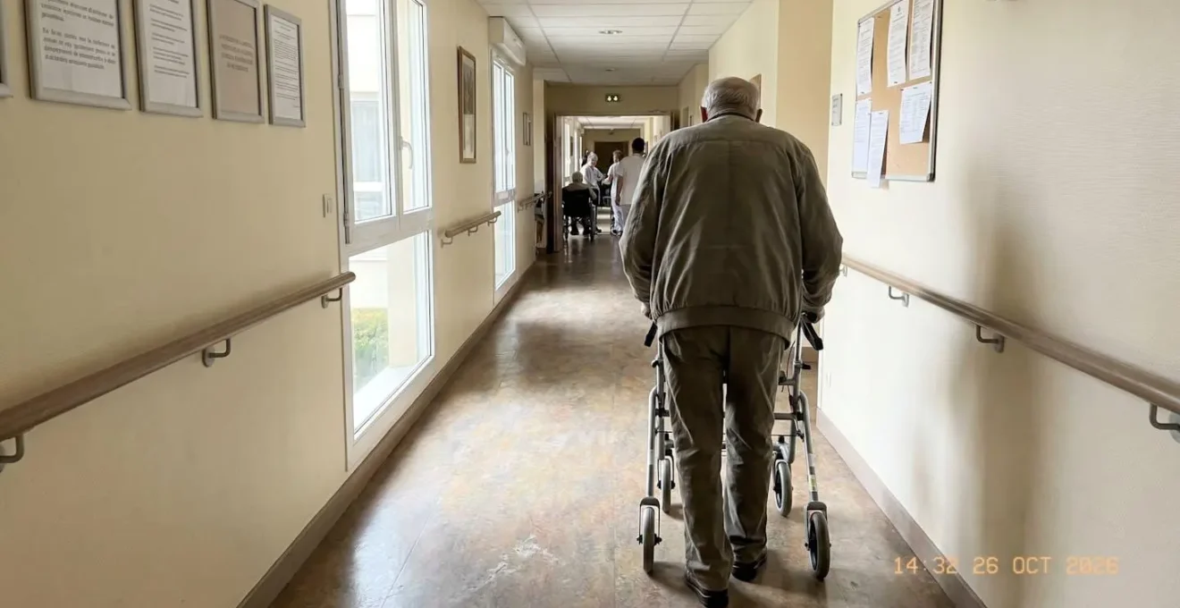 Un résident âgé se déplaçant avec un déambulateur dans un couloir lumineux d
